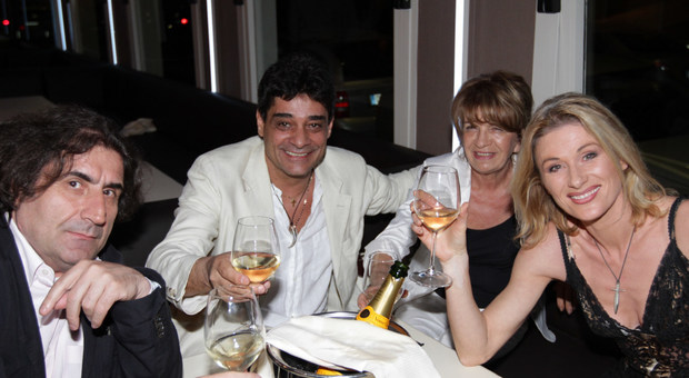Michele Ercole in completo bianco al tavolo con amici