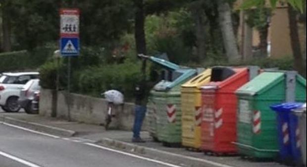 Un cittadino di origini africane intento a rovistare in un bidone della spazzatura Borgo Santa Maria